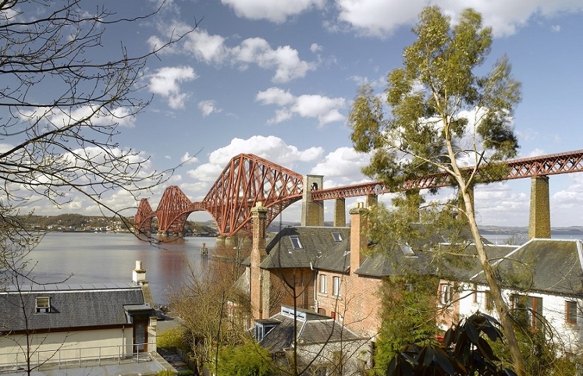 A view over rooftops to the Forth Bridge on a sunny day