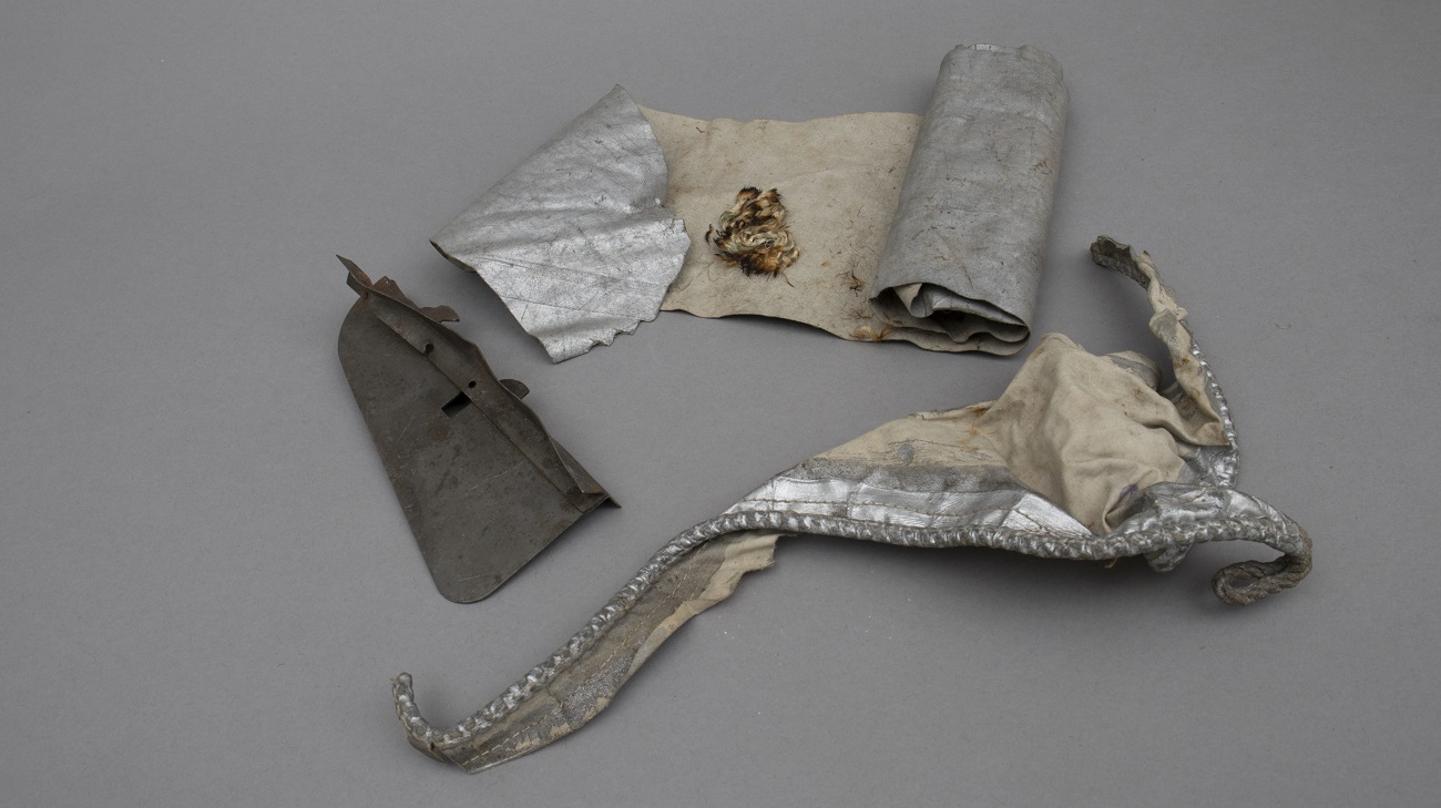 Fragments of bomb, canopy and rope laid out on a grey backgrounf