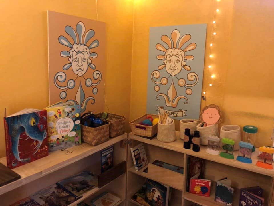 Sensory room corner showing wooden shelves with books and baskets of toys and accessories