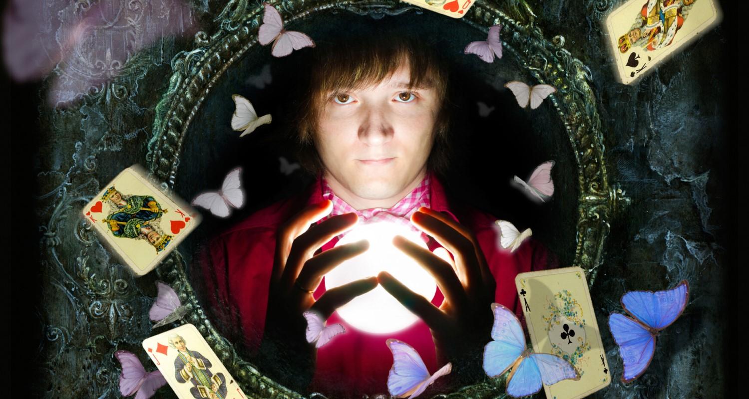 A man holding a glowing globe reflected in a circular gothic mirror with butterflies and playing cards scattered around the edges