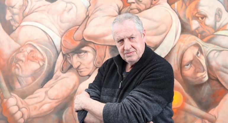 Photo of artist Peter Howson in front of one of his paintings