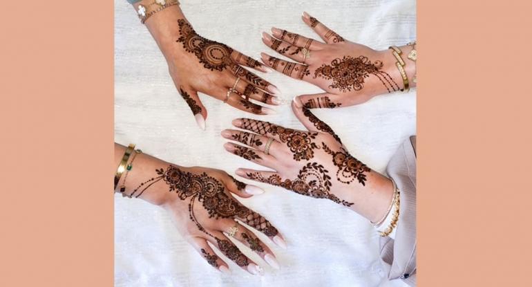 Two pairs of hands decorated with henna against a white background