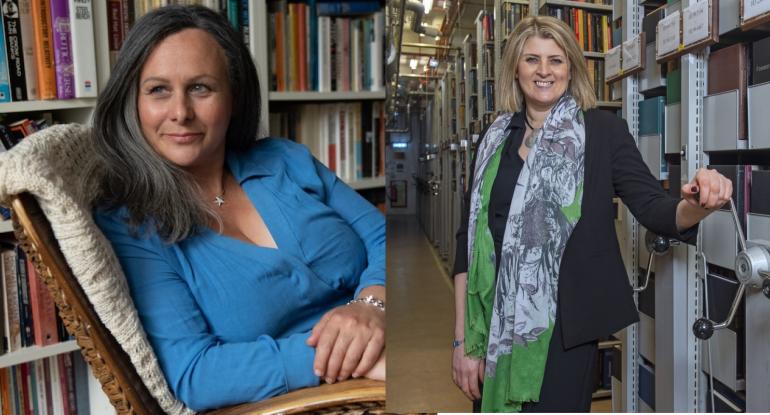 Sara Sheridan wearing a blue top and a mulberry skirt reclining in an arm chair plus Amina Shah, wearing a brown suit and a green and grey scarf, standing inside library stacks