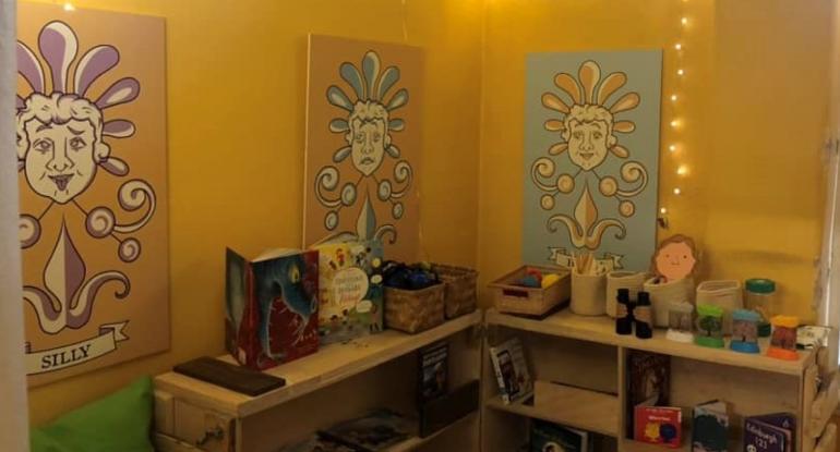 Wall panels, books and shelves of toys in the sensory room. Fairy lights dangle from the ceiling