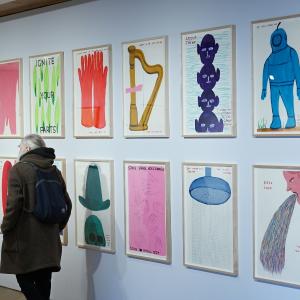 A visitor to the City Art Centre observes a gallery wall of artwork by artist David Shrigley