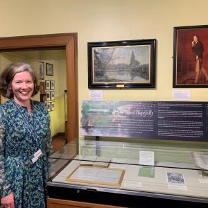 A woman standing next to a display case in a museum. 